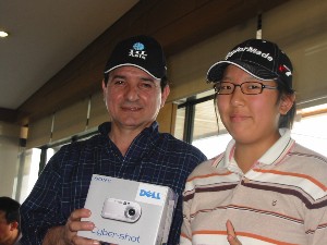 Chapter member Sandra Lee (r) receives a Sony digital camera from Capelo for the Closest to the Pin Drive prize at the golf tournament in April.
